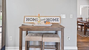 Un comedor con una mesa de madera, dos bancos acolchados y un letrero que dice 'HOME sweet HOME'.