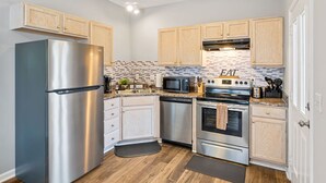 Una cocina moderna con electrodomésticos de acero inoxidable, gabinetes de madera y salpicadero de azulejos.
