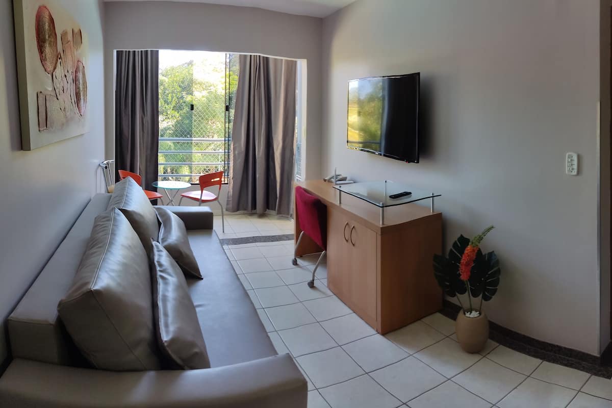 A modern living room with a sofa, a small table, a TV, and a potted plant.