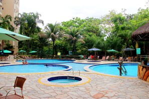 A multi-pool outdoor swimming area with lounge chairs and umbrellas. - Thermas Goiás - Paradise (Rio Quente)