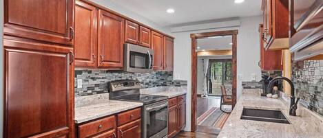 A kitchen with wooden cabinets, stainless steel appliances, and a tiled backsplash.