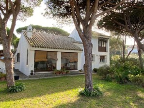 A two-story house with a tiled roof, a covered patio, and a well-maintained garden. - Large house very close to the beach (Roche)