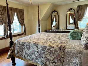 Ein Schlafzimmer mit Himmelbett, einem großen Spiegel und einem Schminktisch.