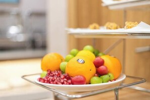 A fruit platter with oranges, grapes, and pomegranate on a metal stand. - Vienna 3 Best Hotel (Huai'an Huaiyin Normal University North Bus Station) (Huai'an)