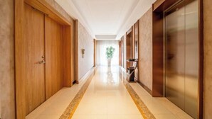 A hotel corridor with wooden doors, a tiled floor, and an elevator. - Vienna 3 Best Hotel (Huai'an Huaiyin Normal University North Bus Station) (Huai'an)