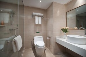 A modern bathroom with a glass shower enclosure, a toilet, a sink with a vase of flowers, and a large mirror. - Vienna 3 Best Hotel (Huai'an Huaiyin Normal University North Bus Station) (Huai'an)