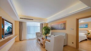 A hotel room with a large bed, a seating area with a sofa and armchairs, a TV, and a painting on the wall. - Vienna 3 Best Hotel (Huai'an Huaiyin Normal University North Bus Station) (Huai'an)