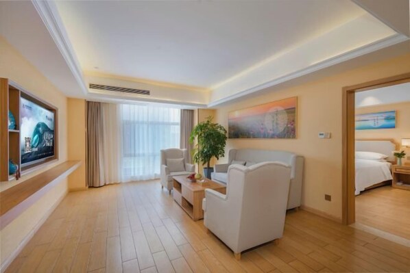 A hotel room with a large bed, a seating area with a sofa and armchairs, a TV, and a painting on the wall. - Vienna 3 Best Hotel (Huai'an Huaiyin Normal University North Bus Station) (Huai'an)