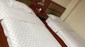 A hotel room with a large bed, a wooden headboard, and a small bedside table with a lamp. - Mengcheng Jiayue Hotel (Mengcheng)