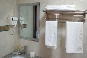 A bathroom with a hairdryer, towel rack, and a mirror.
