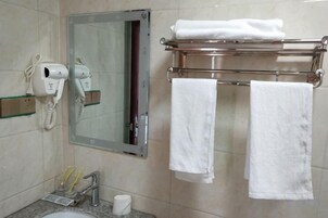 Un baño con secador de pelo, toallero y espejo.