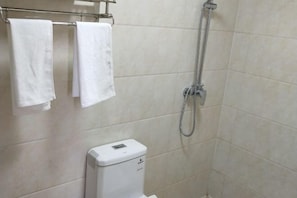 A bathroom with a shower, two towels hanging on a rack, and a toilet.