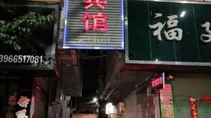 A narrow alley with various storefronts, including a brightly lit sign for a business. - Mengcheng Jiayue Hotel (Mengcheng)