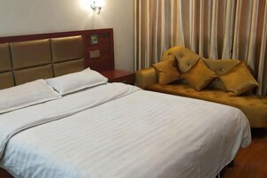 Una habitación de hotel con una cama, un sofá y una mesita de noche.