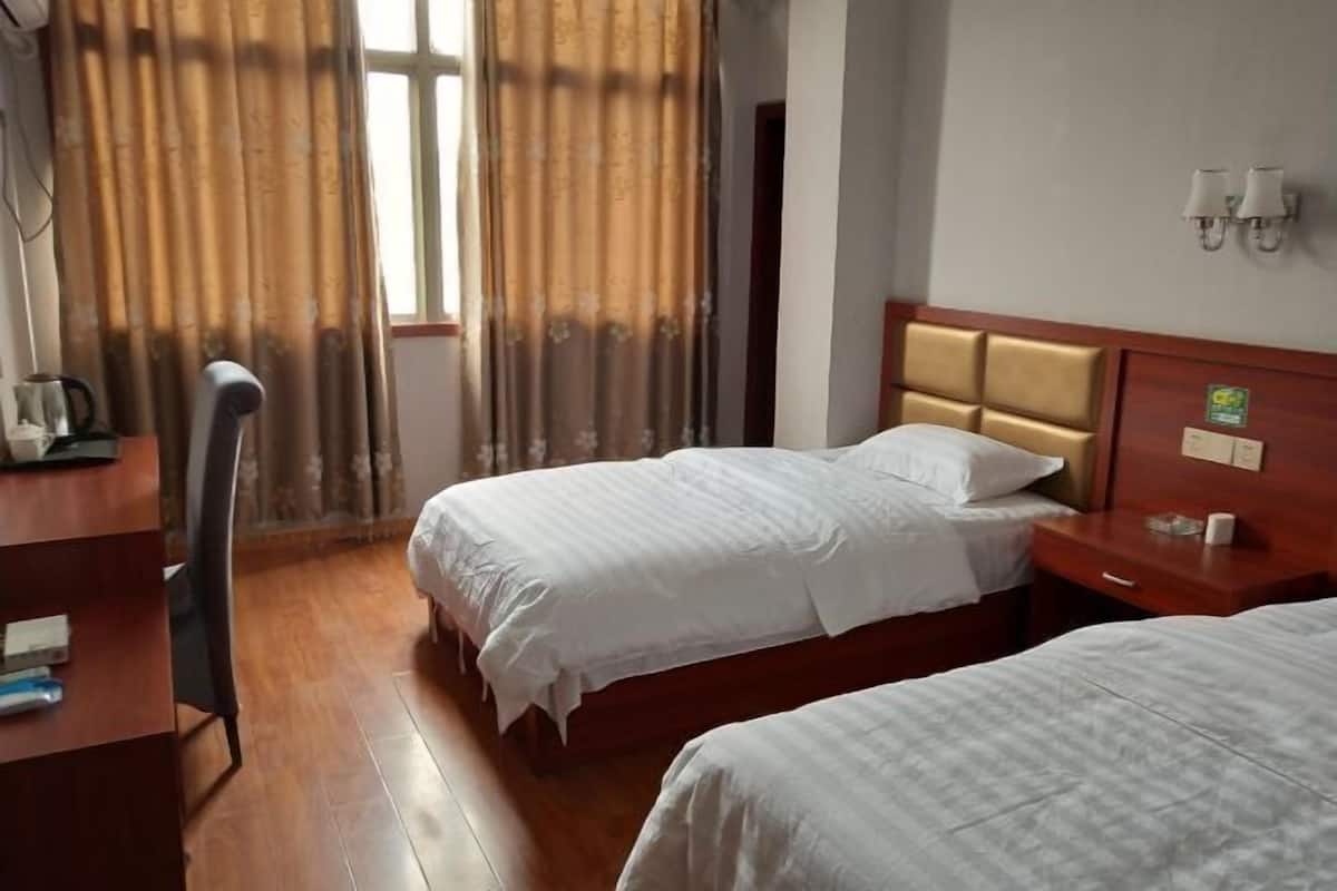 Ein Hotelzimmer mit zwei Betten, einem Schreibtisch und einem Stuhl.