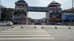 A street view with a pedestrian crossing, buildings, and parked cars. - Mengcheng Jiayue Hotel (Mengcheng)