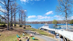 Vista al lago con un muelle de madera, un pequeño embarcadero y una fila de sillas Adirondack de colores.