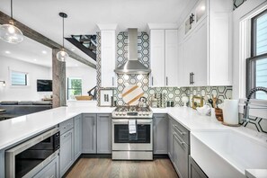 A modern kitchen with grey cabinets, a stainless steel stove, and a hexagonal backsplash.