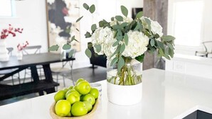 A kitchen counter with a vase of flowers and a bowl of green apples. - Miracle on 54th - Hot Tub, Sauna, and Pickleball (Cleveland)