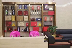 Een receptiebalie met een presentatie van diverse voorwerpen, waaronder dozen en flessen, en een zithoek met een bank en een plant.