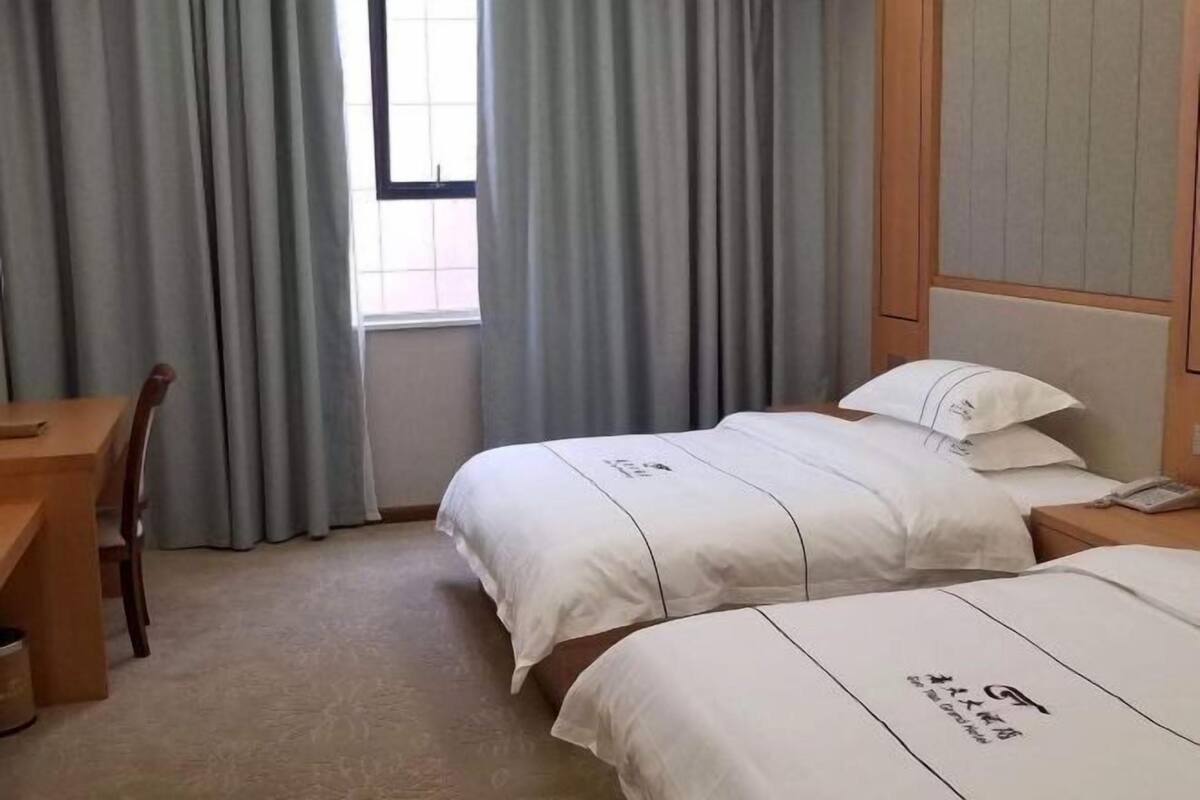 Une chambre d’hôtel avec deux lits, un bureau et une chaise.