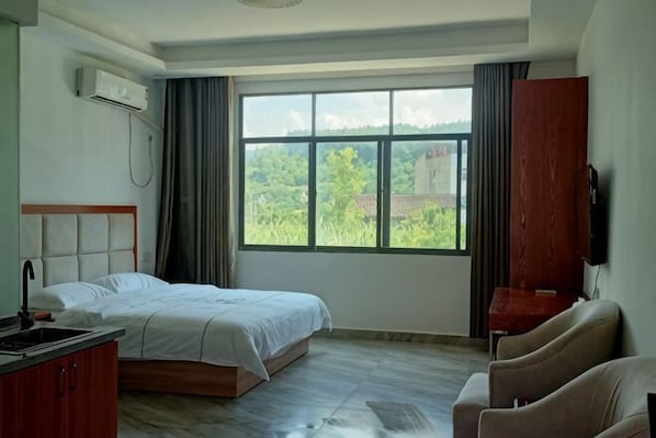 Ein Hotelzimmer mit einem Bett, einem Schreibtisch mit Stuhl, einem Fernseher und einem großen Fenster mit Blick.