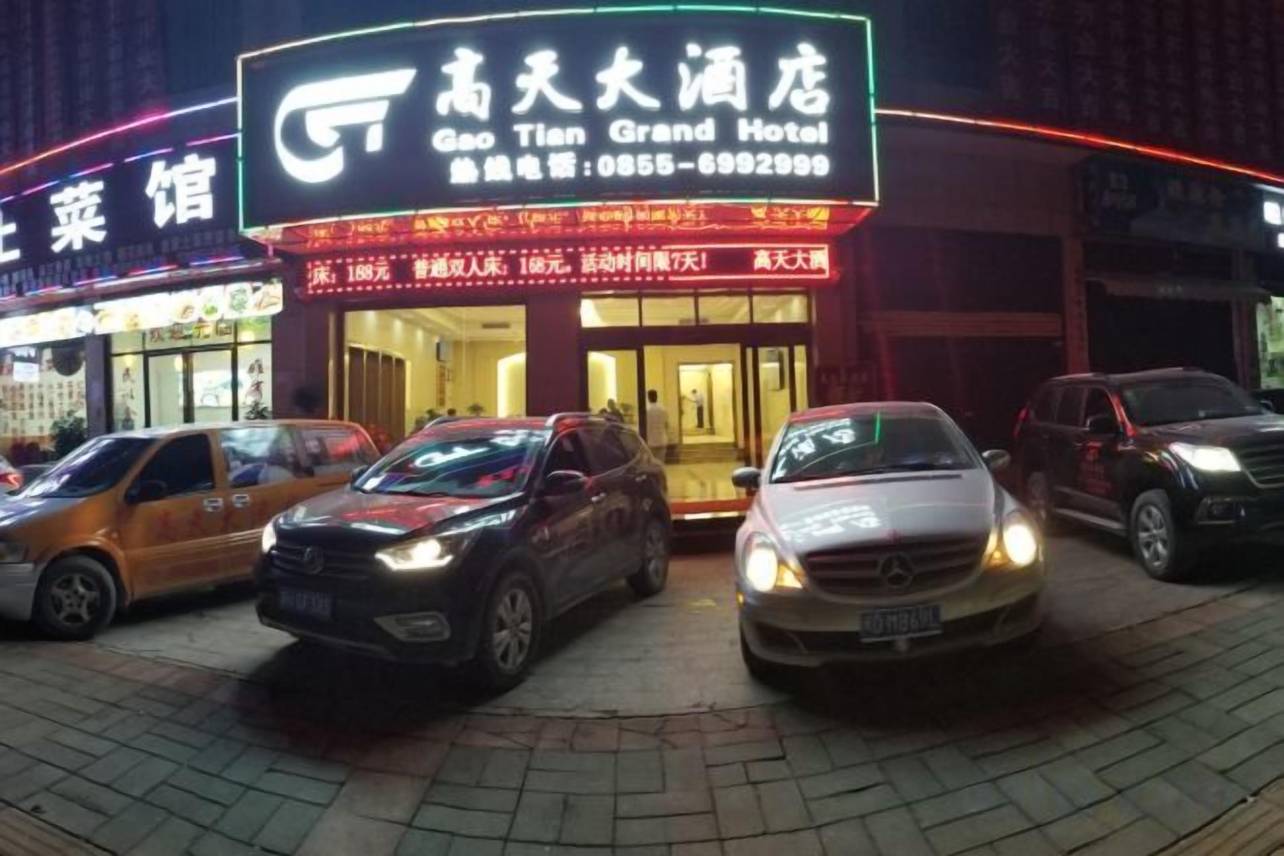 A hotel with a prominent sign, multiple cars parked in front, and a visible entrance.