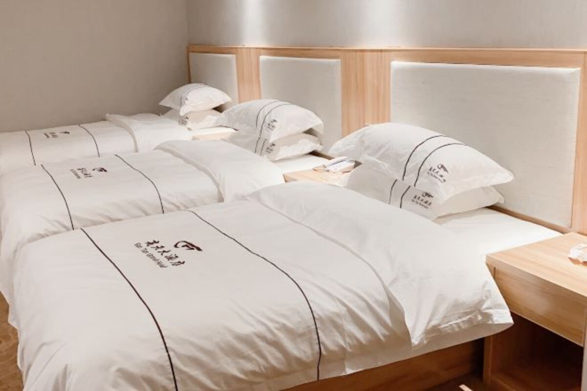 Une chambre d’hôtel avec deux lits, chacun doté de draps et d’oreillers blancs, et d’une tête de lit en bois.