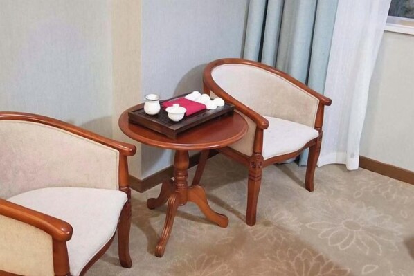 Ein Zimmer mit zwei Holzsesseln und einem kleinen runden Tisch mit einer Tablett-Auslage.
