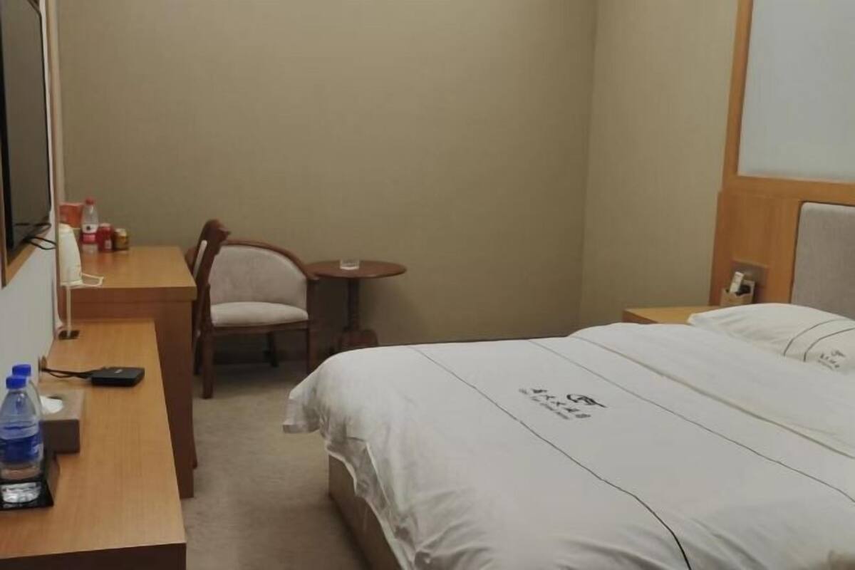Une chambre d’hôtel avec un lit, un bureau, une chaise, une petite table et un téléviseur.