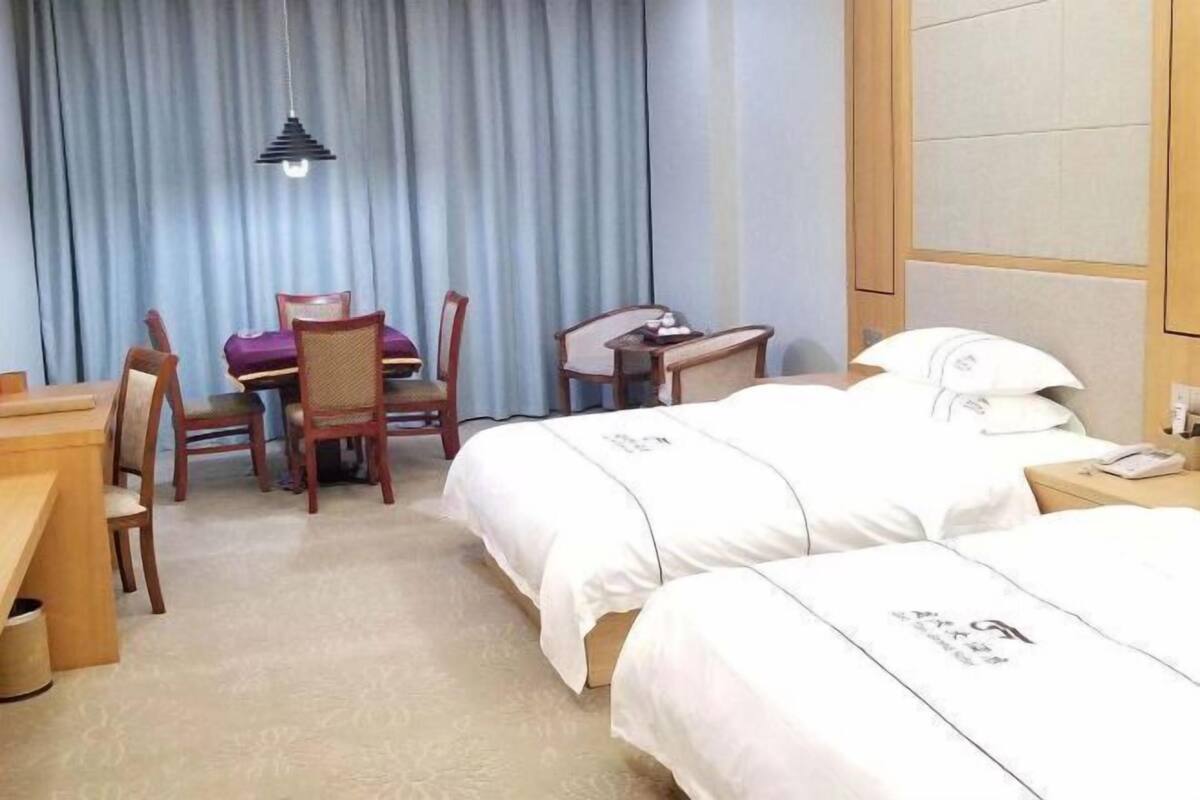 Une chambre d’hôtel avec deux lits, un bureau, une chaise et une table à manger.