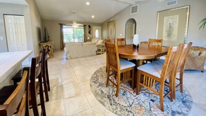 A spacious dining area with a round wooden table, multiple chairs, and a patterned rug. - Vanderbilt Beach Retreat- 4 Bed 1-level, Spacious, & Pet-Friendly - 3 King Beds (Naples)