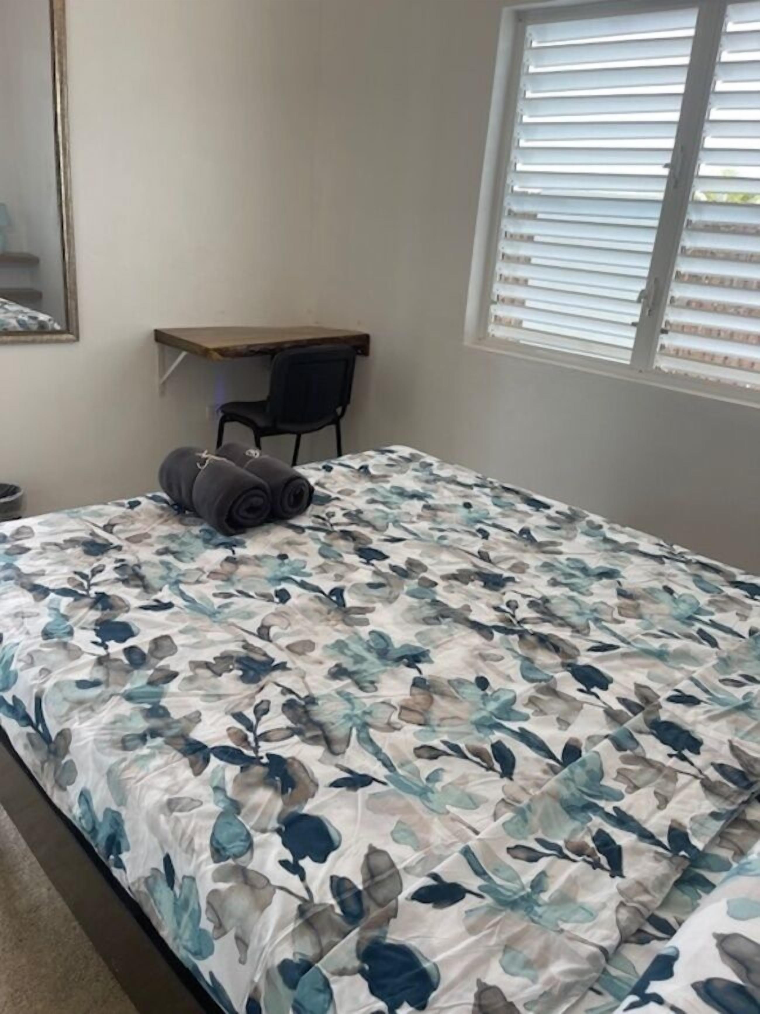 A bedroom with a bed, a desk, and a chair.