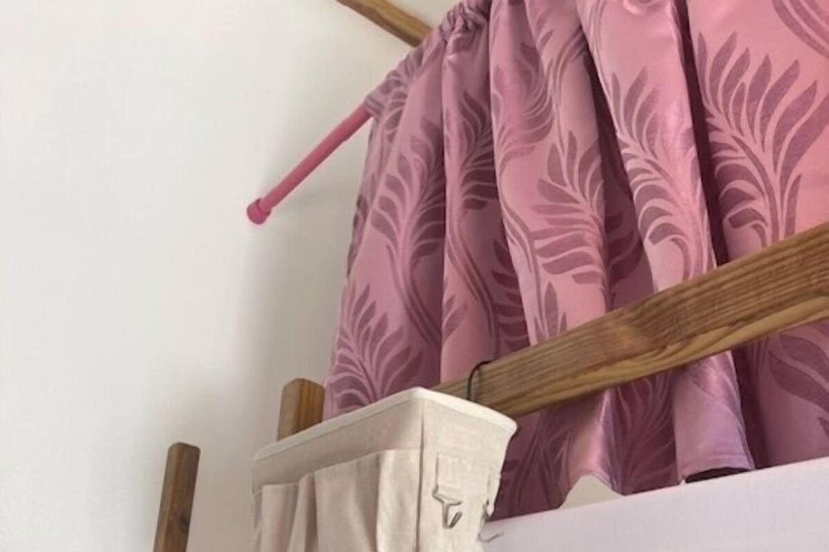 Estrutura de cama de madeira com colchão e colcha floral rosa.