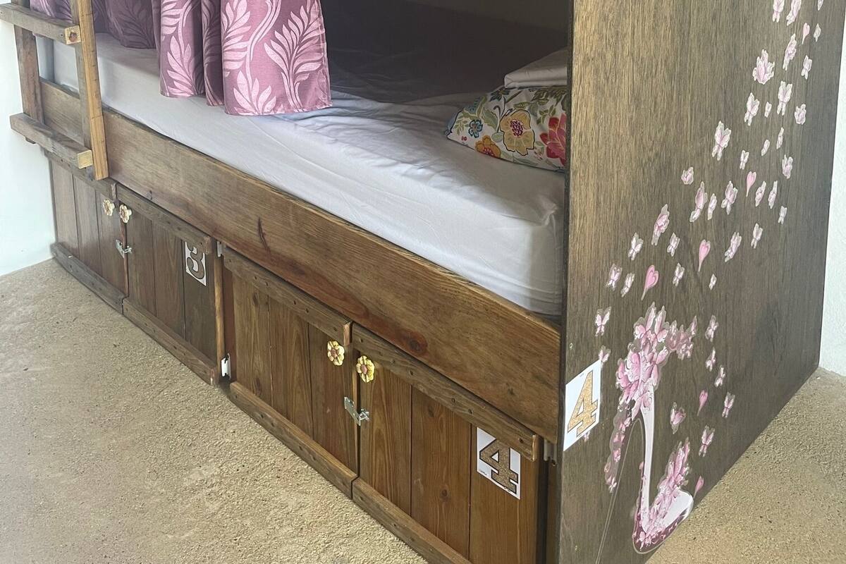 Uma cama de beliche com escada, um armário de armazenamento e um adesivo decorativo com o número '3'.