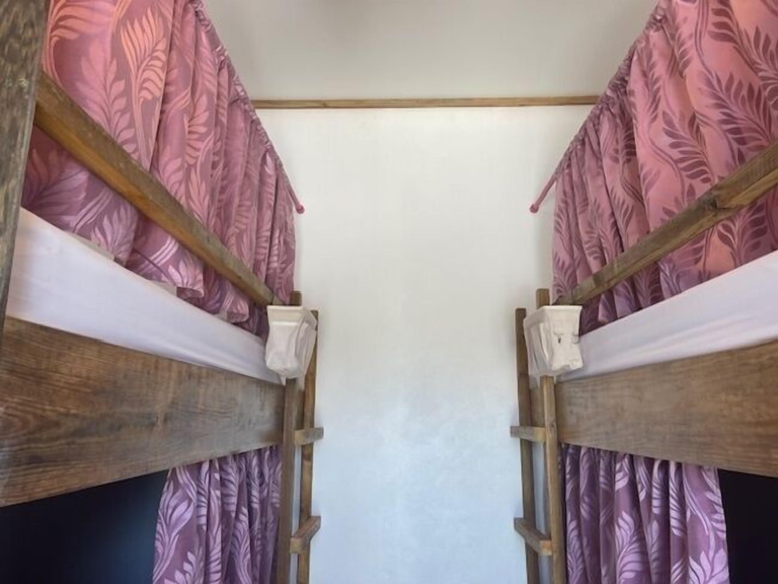 A bunk bed room with a wooden frame and pink patterned curtains.