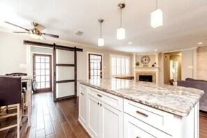 A spacious kitchen with a large island, white cabinetry, and pendant lighting. - The Live Oak Place - Park Access - Serene Retreat! (Stafford)