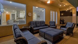 A cozy living area with wicker furniture, a large mirror, and string lights. - Your AZ Oasis, Heated pool and cleaning fee are all included for free! (Goodyear)