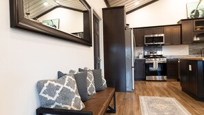 Eine moderne Küche mit Edelstahlgeräten, einer Holzbänklage mit Kissen und einem großen Spiegel an der Wand.