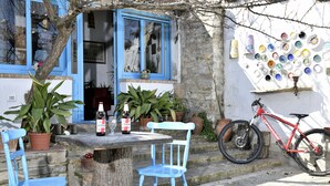 A rustic outdoor seating area with a table, chairs, and a bicycle. - The pergola (old house) inside the history of Sardinia. (Gergei)