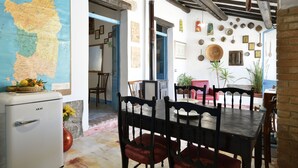 A dining area with a map, wooden chairs, and a vintage refrigerator. - The pergola (old house) inside the history of Sardinia. (Gergei)