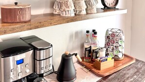 Un taulell de cuina amb equipament per fer cafè, un rètol de cafeteria i objectes decoratius.