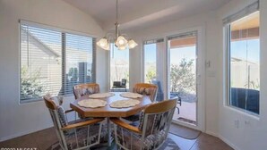 A dining area with a round table, six chairs, and a chandelier.