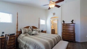 A bedroom with a bed, wooden nightstands, a dresser, a ceiling fan, and a window.