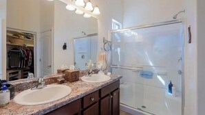 A bathroom with two sinks, a large mirror, and a glass shower enclosure.