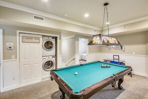 A laundry room with a pool table and a hanging light fixture.