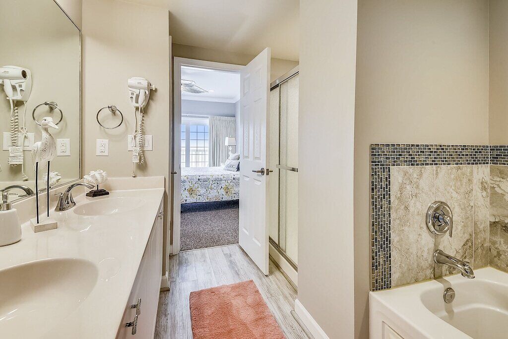 A hotel bathroom with a large sink, a bathtub, and a shower. There is a mirror above the sink and a towel rack.
