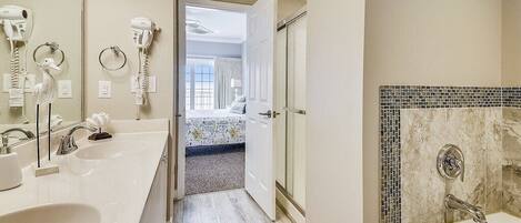 A hotel bathroom with a large sink, a bathtub, and a shower. There is a mirror above the sink and a towel rack.