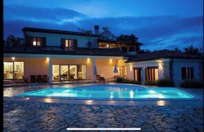 Enjoy a refreshing swim in the pool surrounded by the house's large windows and stone exterior.