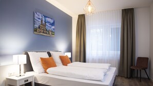 A modern hotel room with a large bed, a bedside table with a lamp, a chair, and a window with curtains. - Villa am Bahnhof (Fulda)